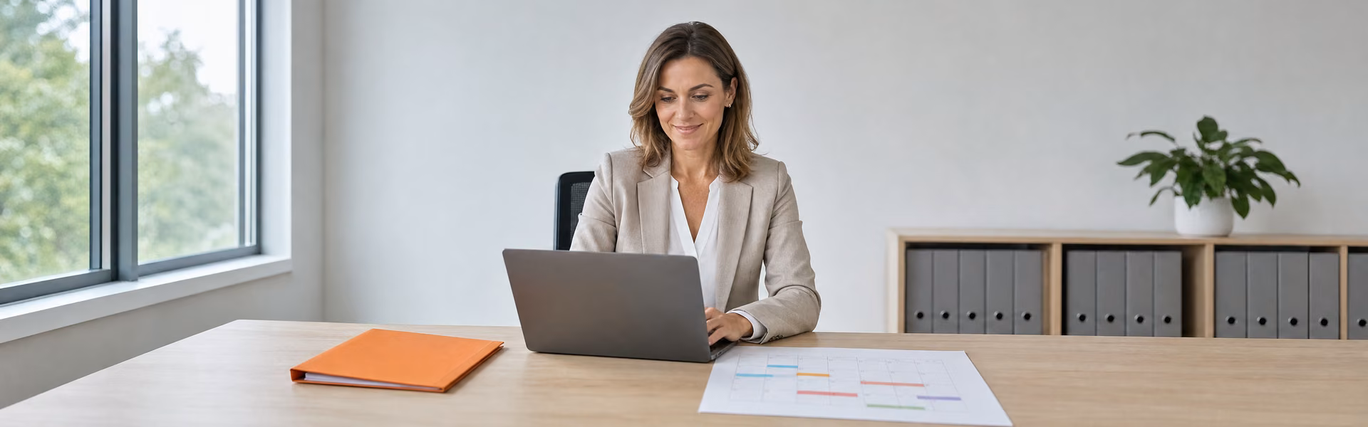 Personalerin prüft am Laptop die Arbeitsunfähigkeitszeiten eines Mitarbeiters, daneben ein Kalender mit markierten Zeiträumen