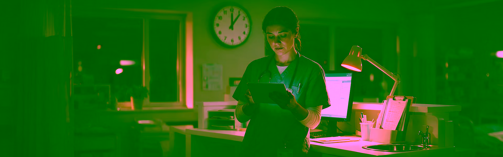 Pflegekraft prüft im Nachtdienst auf der Station den Dienstplan auf einem Tablet, im Hintergrund eine Wanduhr kurz nach Mitternacht