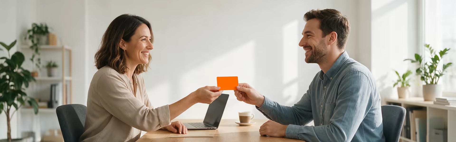 Arbeitgeberin überreicht einem Mitarbeiter im Büro eine Gutscheinkarte als steuerfreien Sachbezug